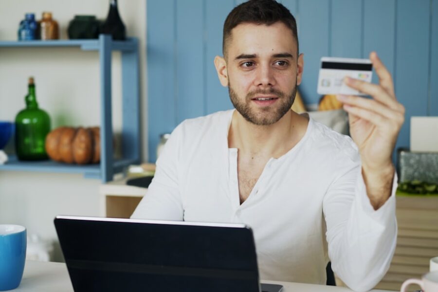 Man holding credit card while looking at laptop