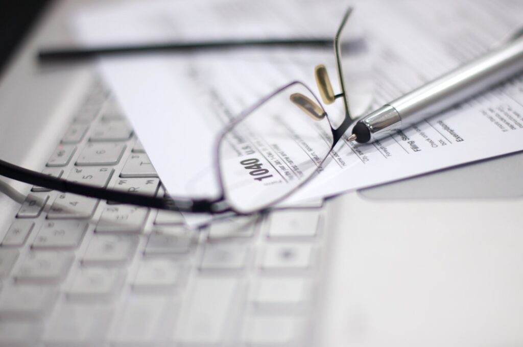 Glasses and pen on tax form and laptop.