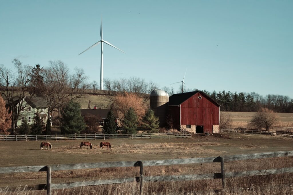 Rural farm with horses and wind turbine.